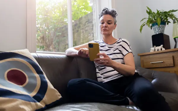 Woman sitting on the couch, looking at her phone. 