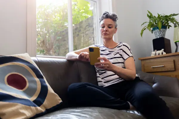 Woman sitting on the couch, looking at her phone. 